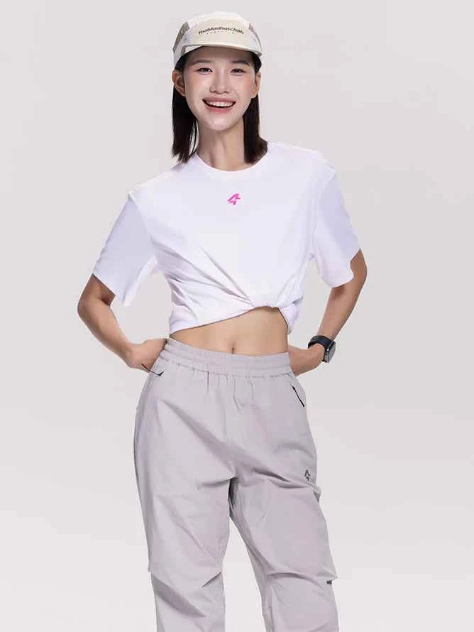 Vit kortskuren t-tröja med litet rosa logo ihop med kakifärgade unisex cargo sweatbyxor för fritidsbruk