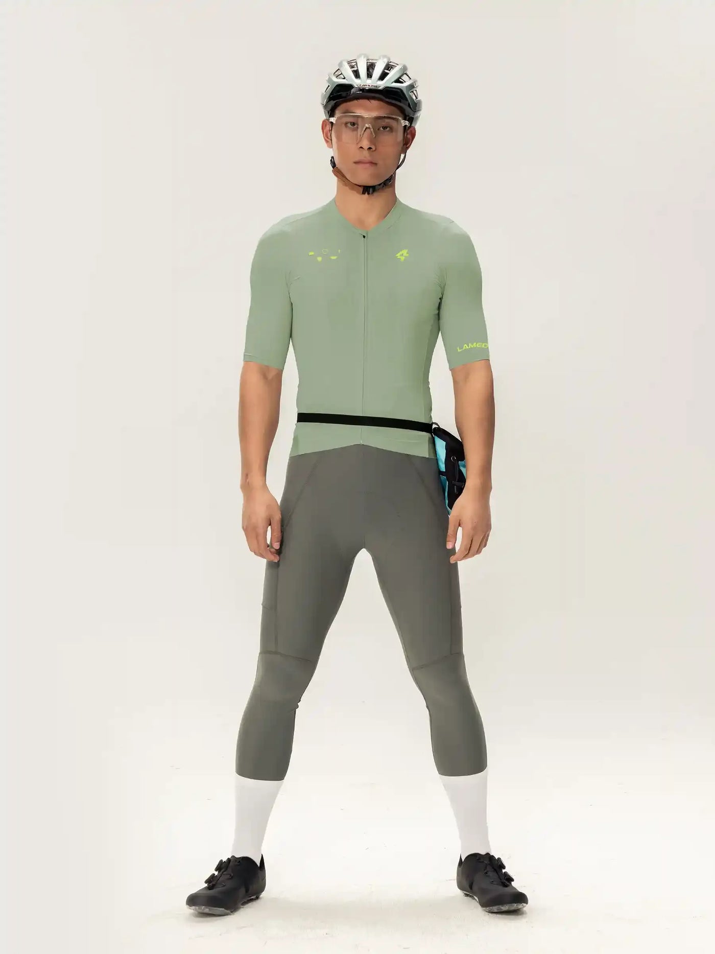 En man som bär roam kortärmad herrcykeltröja i ljusgrönt med svarta kanter och neongula detaljer tillsammans med grå tights