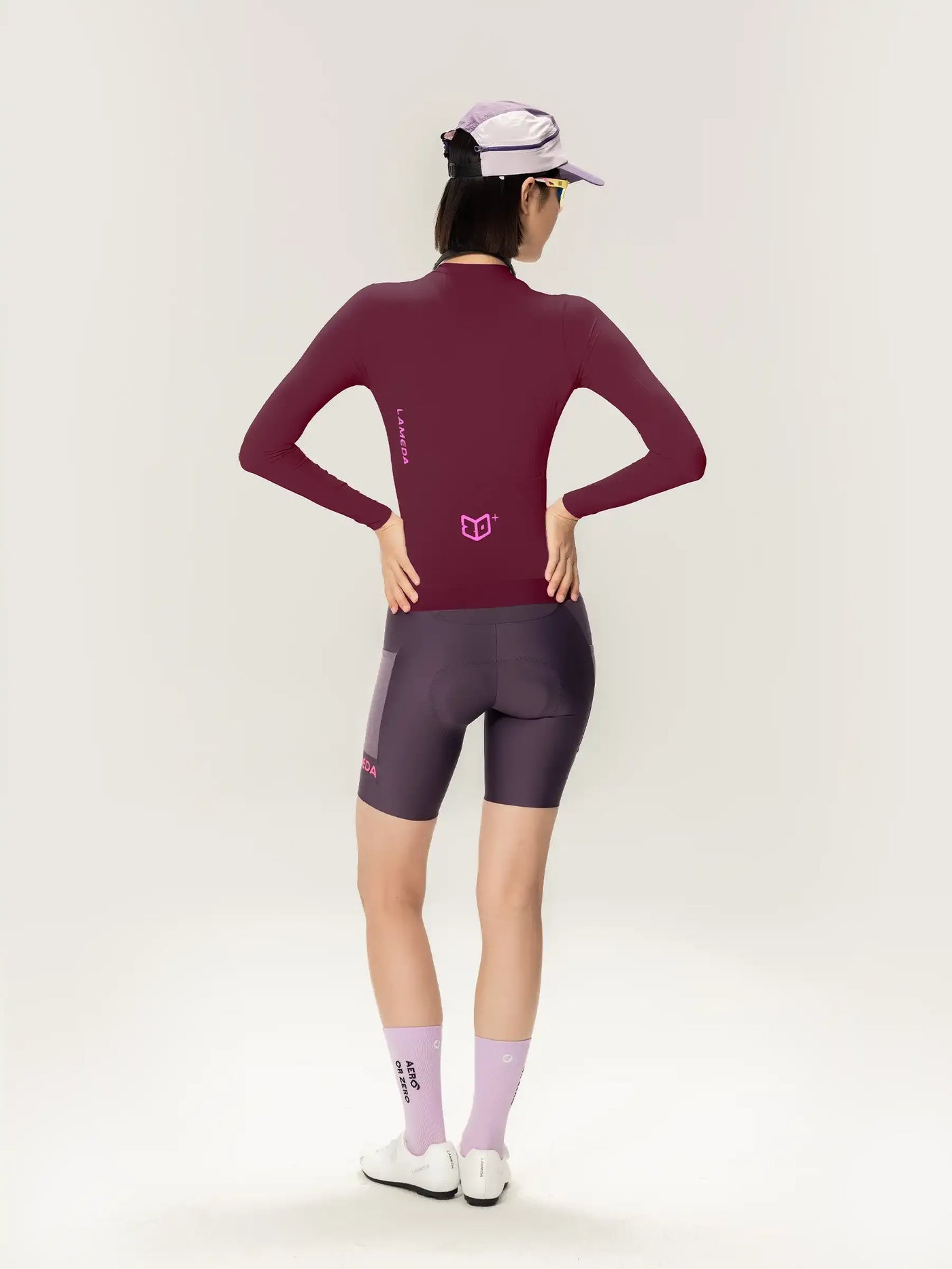 Rödbrun långärmad cykeltröja med rosa logotyp och matchande mörkgrå cykelshorts för kvinnor i purple roam collection