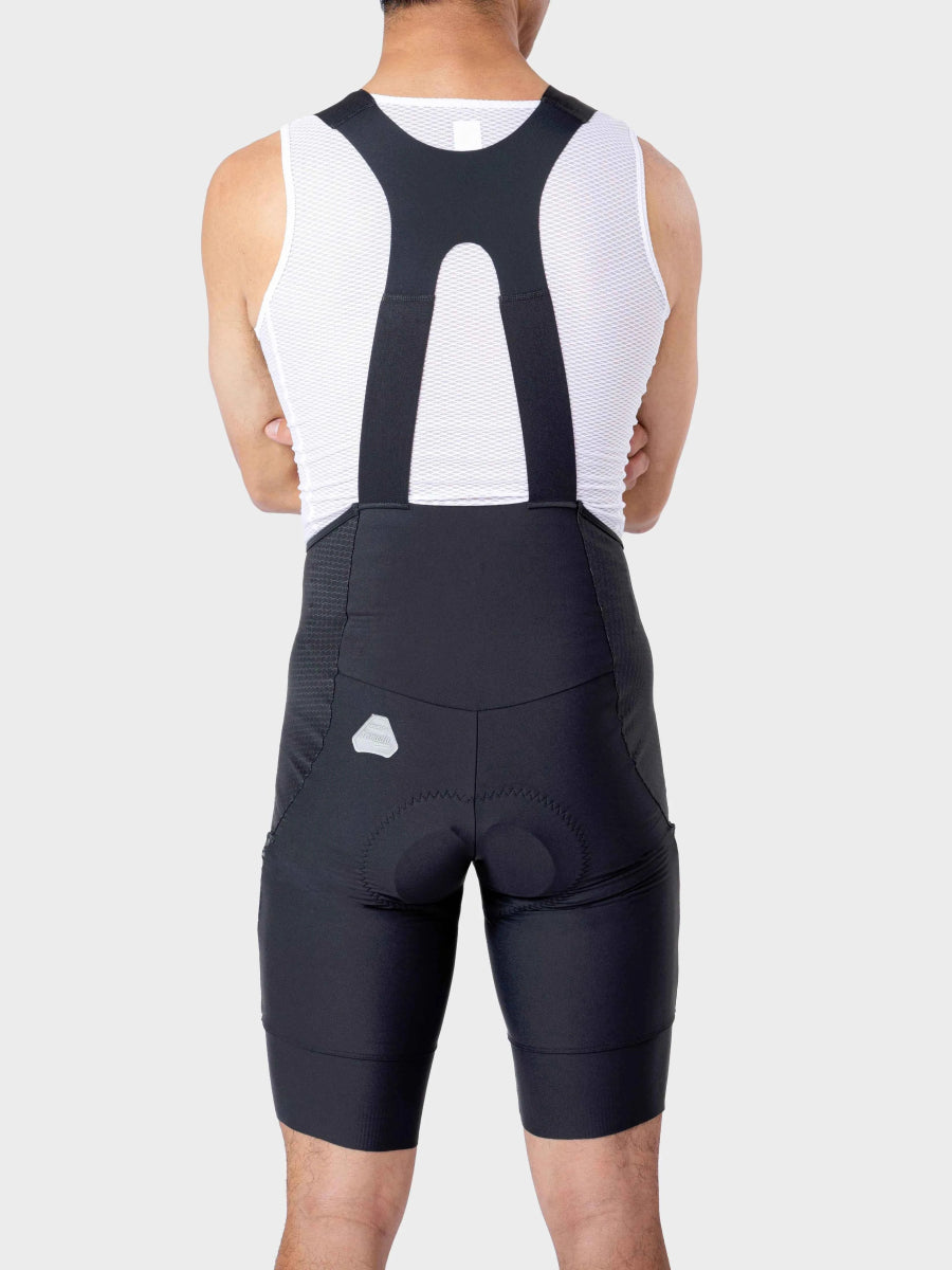 Black men’s bib shorts with padded seat and supportive straps in jacquard fabric worn over white mesh tank top azure drift