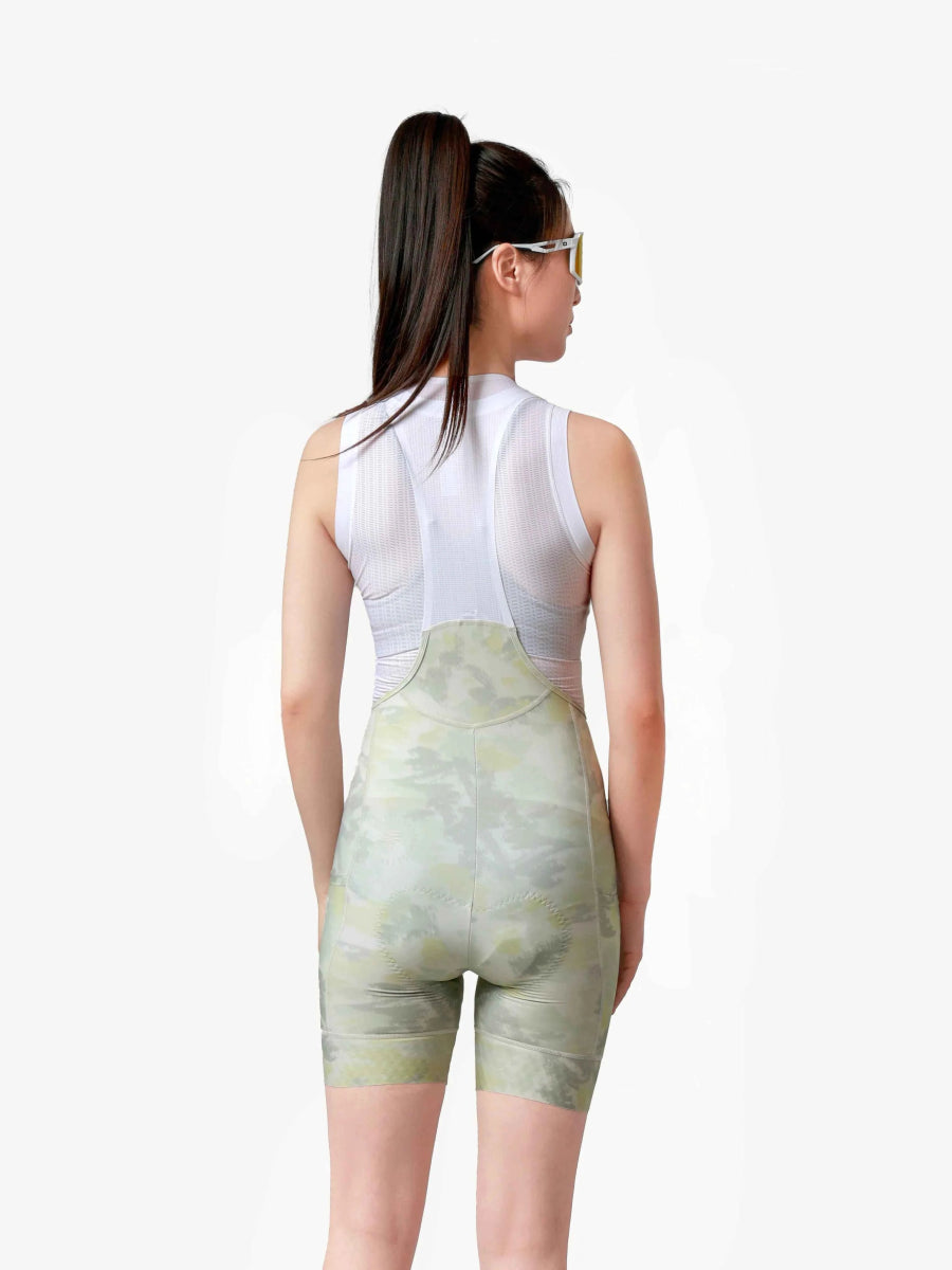 En kvinna bär vita och salviagröna blommönstrade damcykelhängselshorts med nätpaneler från LAMEDA