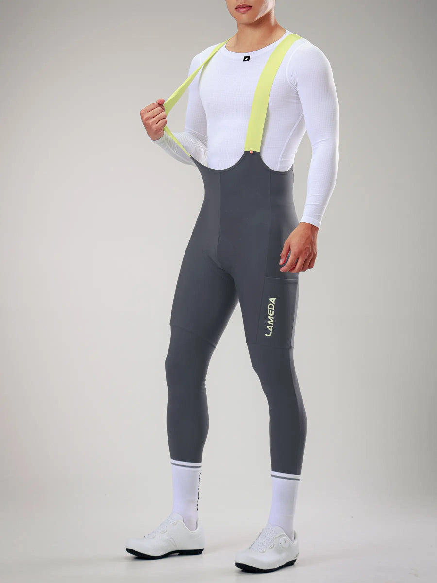 Mörkgrå LAMEDA herrars vinterbibtights med neongula elastiska gränssnittshängsel och vit logotyp på låret