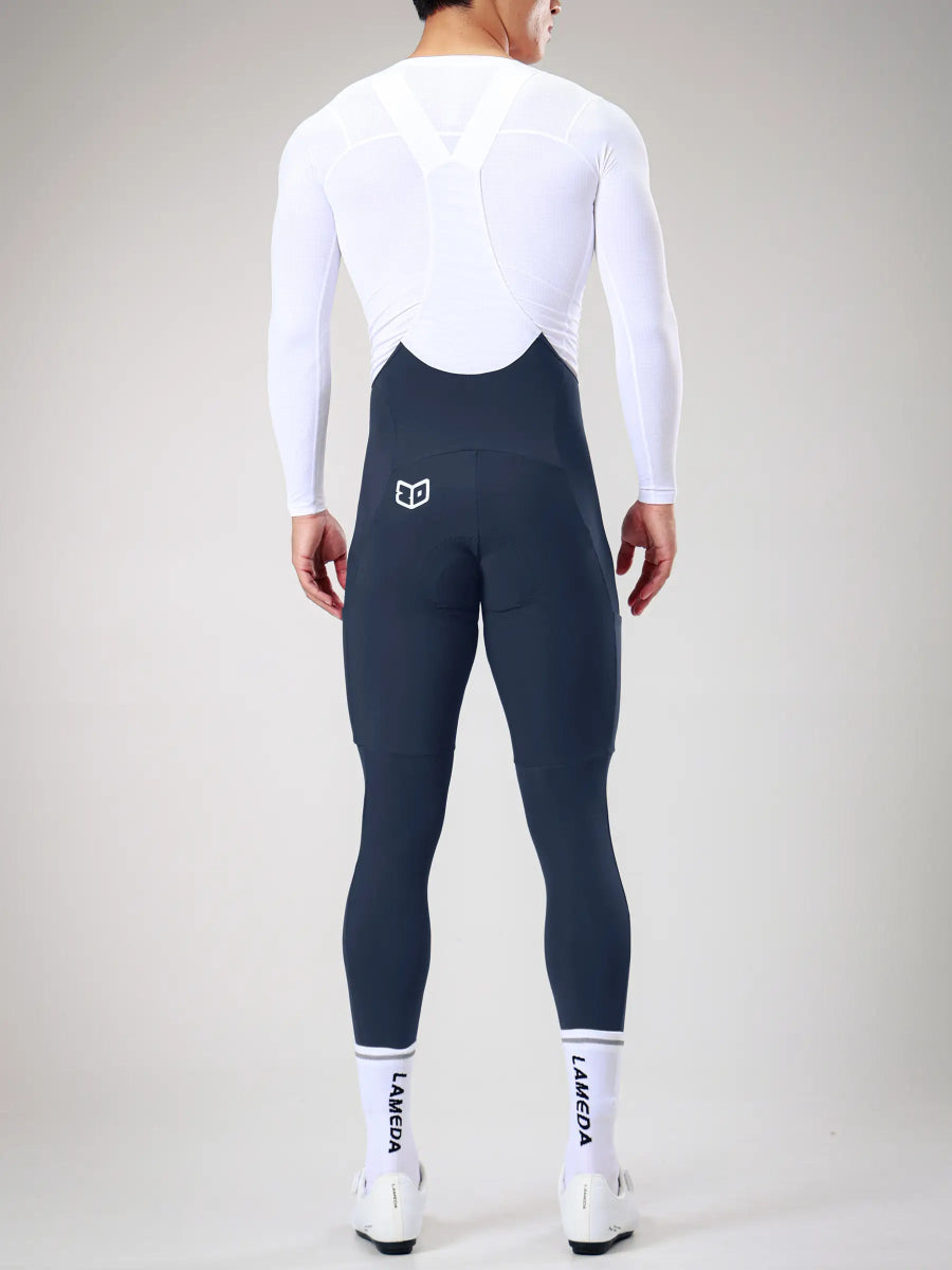 Mörk marinblå LAMEDA herrars vinterhängselcykeltights med elastisk anslutning och vit logo på baksidan kombinerade med långärmad cykeltröja