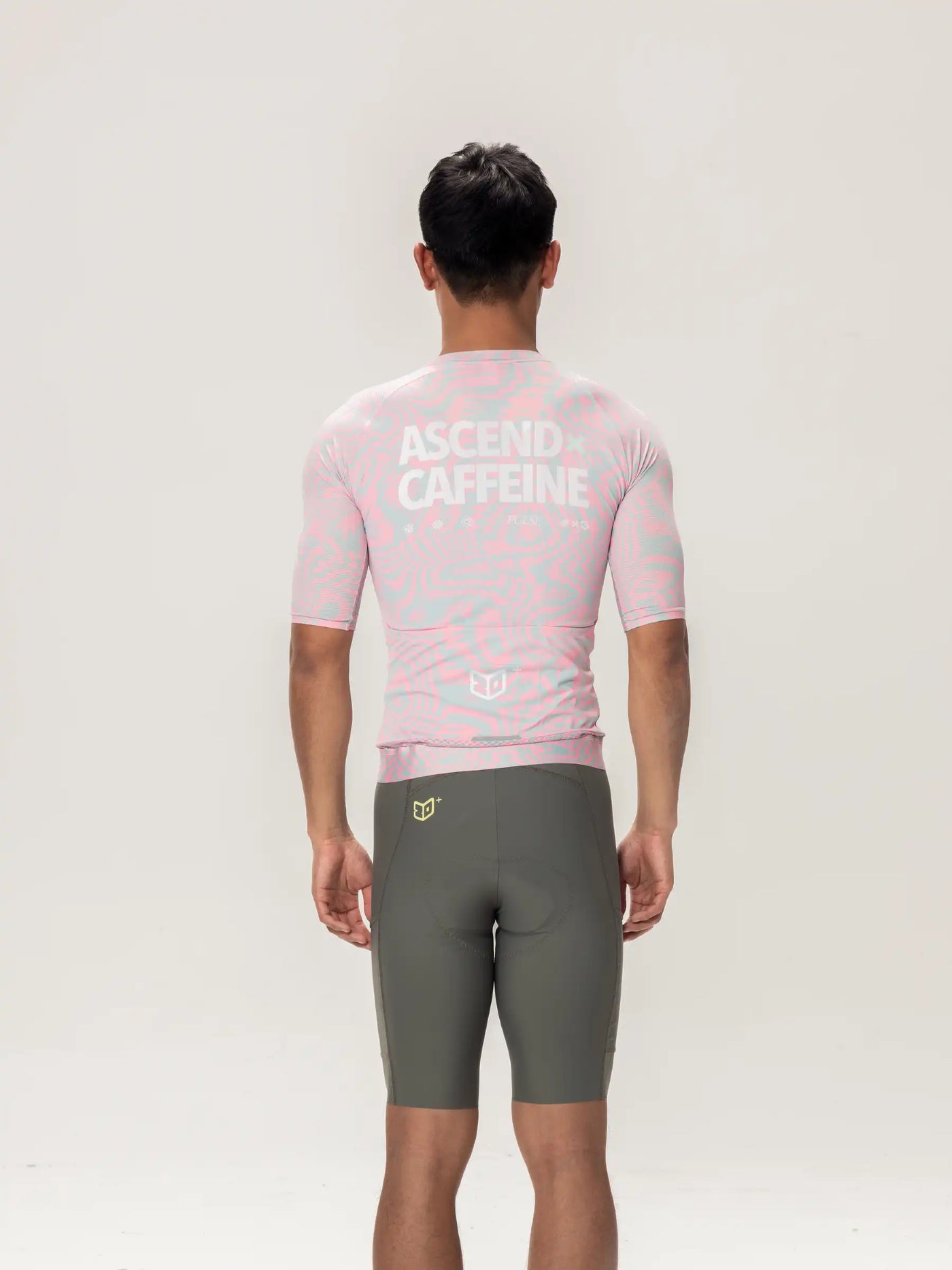 Baksida av persikafärgad LAMEDA x australian studio unisex cykeltröja med diskret geometriskt mönster och texten ascend caffeine
