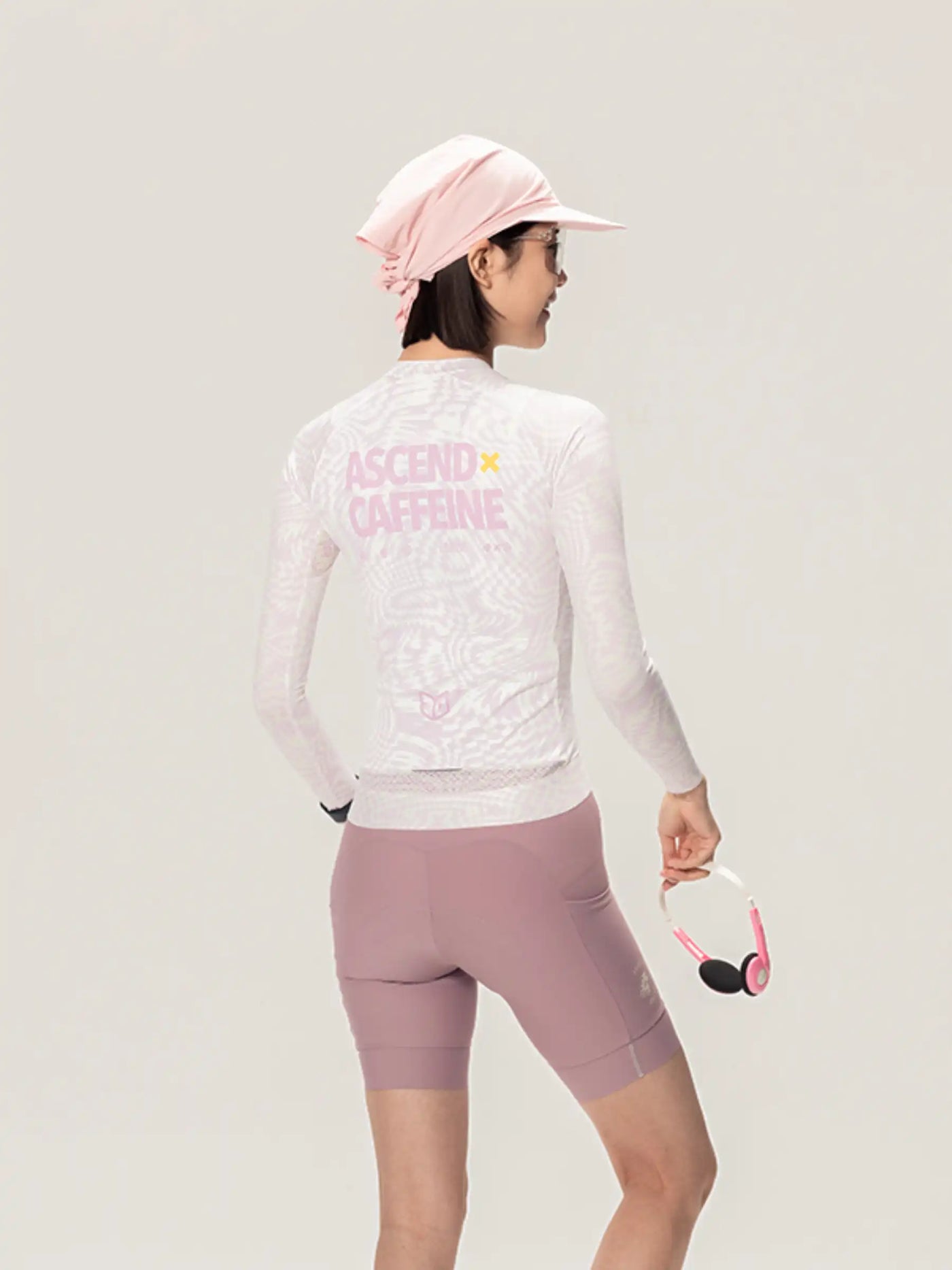 Vit långärmad unisex cykeltröja med rosa ascend caffeine-text och mauve shorts från LAMEDA x australian studio