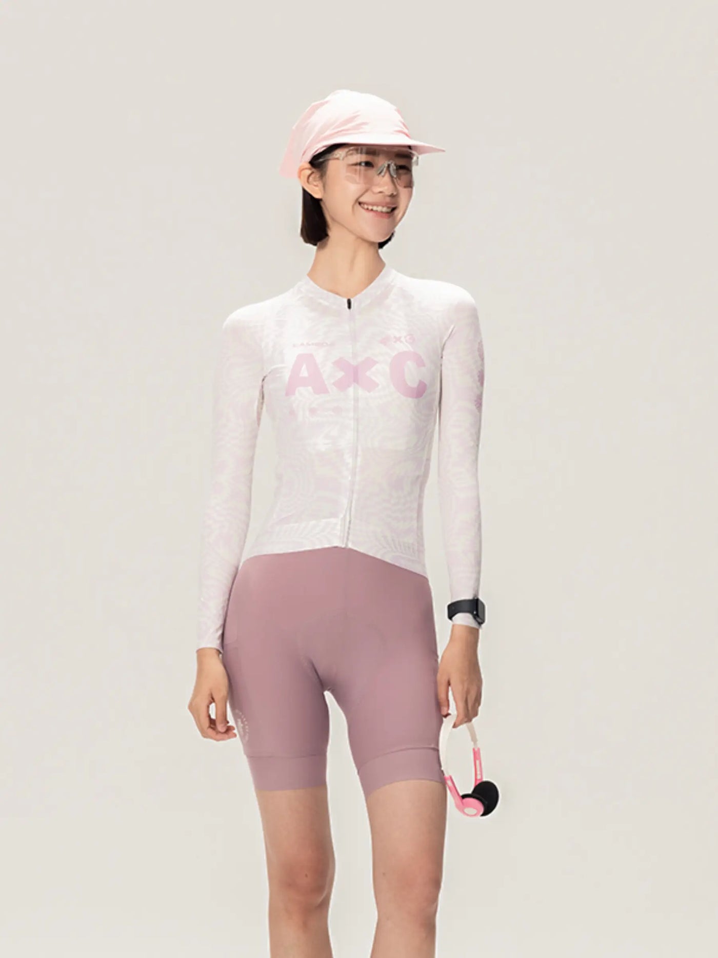 En kvinna bär vit och rosa LAMEDA x australian unisex cykeltröja med mauve shorts i studio unisex cykelstil