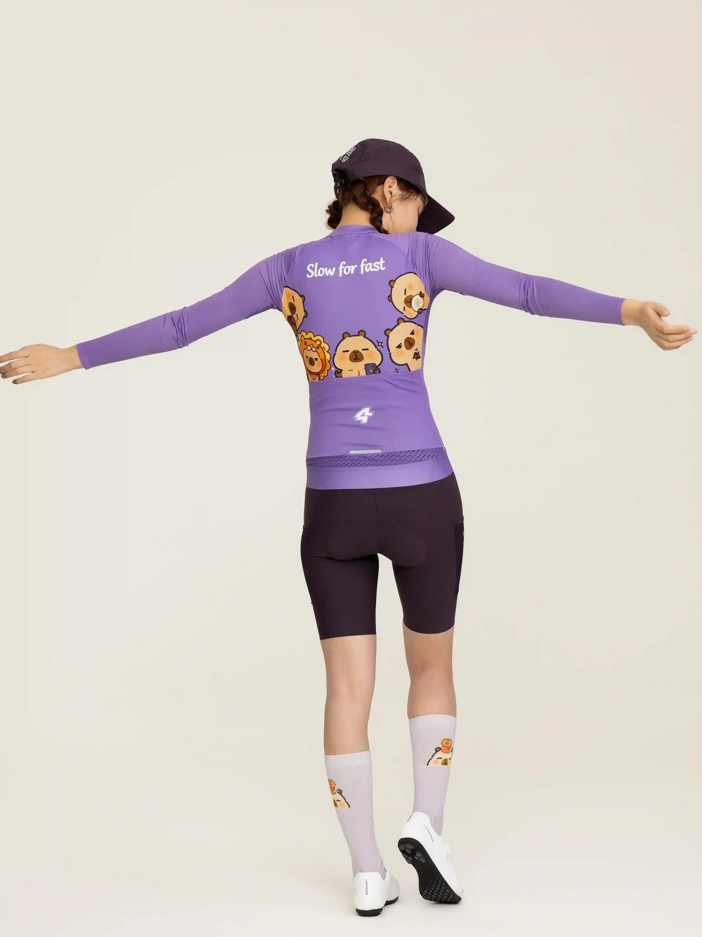 Baksida av lila LAMEDA x capybara långärmad studio unisex cykeltröja med tecknad capybara och text slow for fast