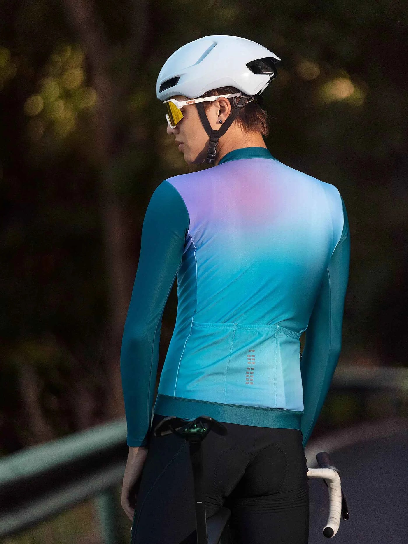 Vit cykelhjälm med strömlinjeformad aerodynamisk design och svarta ventilationsöppningar parat med färgrik unisex fleecefodrad värmande cykeltröja grön
