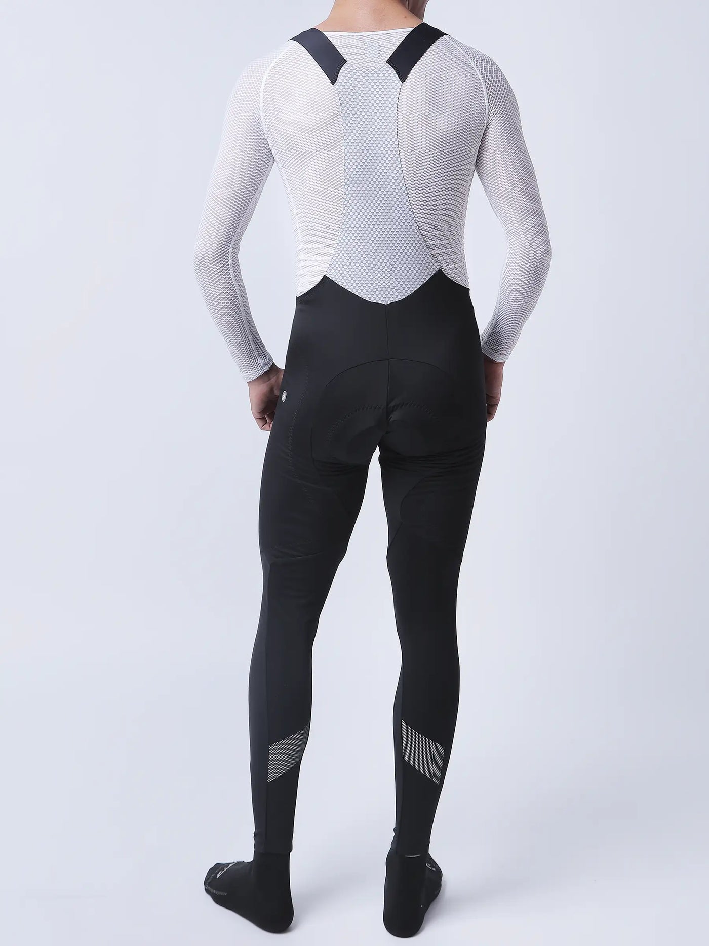 Men’s black cycling bib tights with fleece-lined thighs and reflective calf panels paired with white mesh long-sleeve top