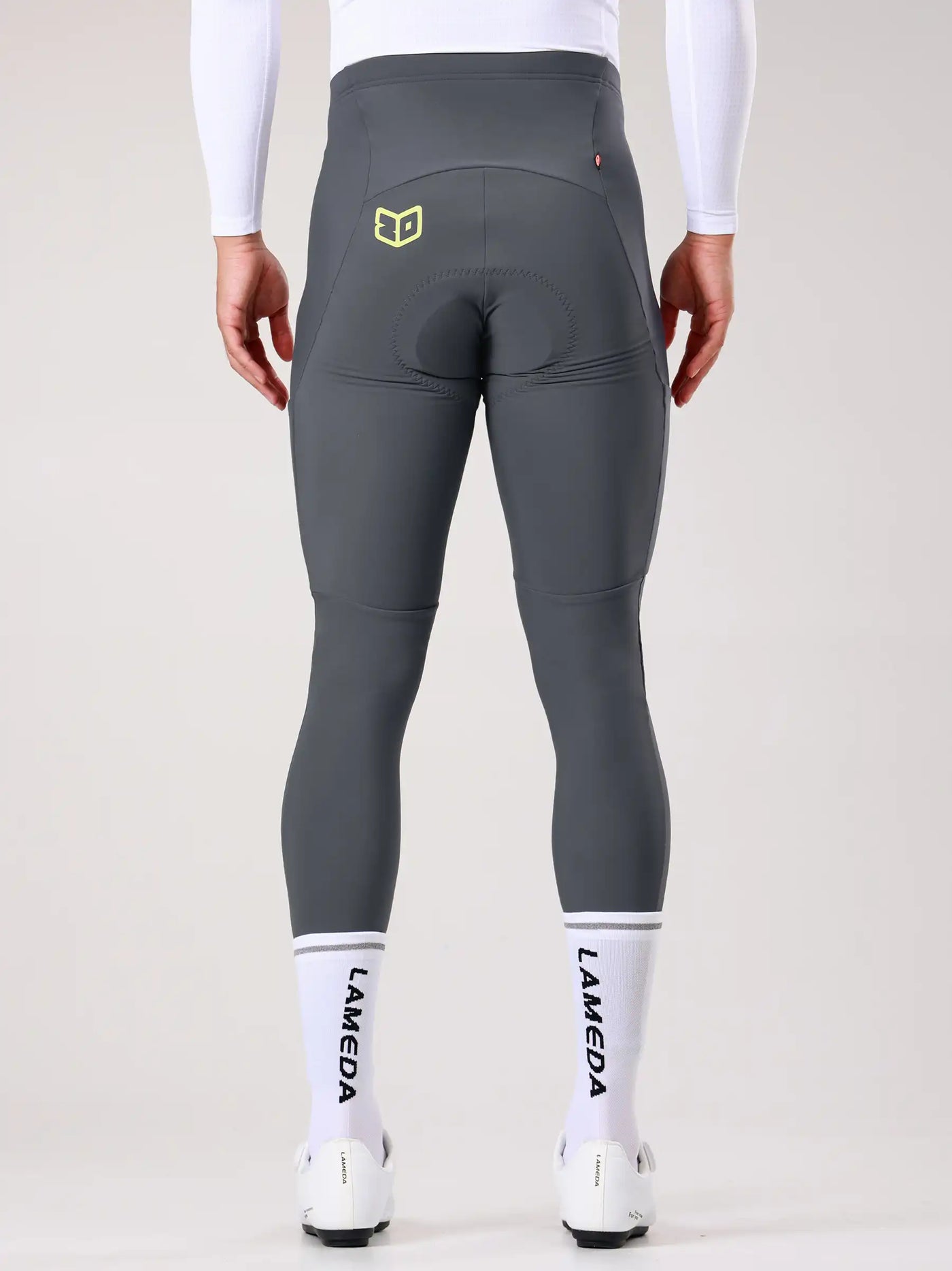 Back view of lameda 20th anniv special men’s thermal cycling tights in dark gray with elastic interface thigh construction and yellow logo