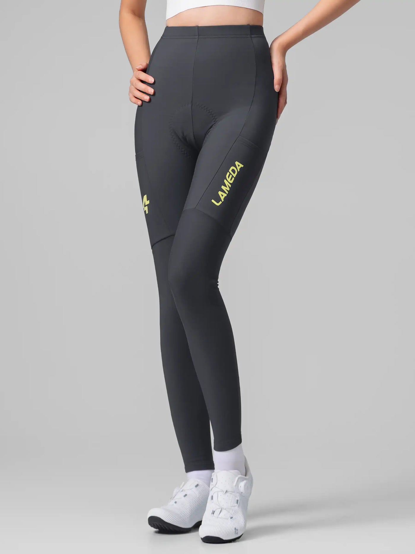 Mörkgrå LAMEDA damcykeltights med neongul logotyp på låret och Elastic Interface® för termisk komfort
