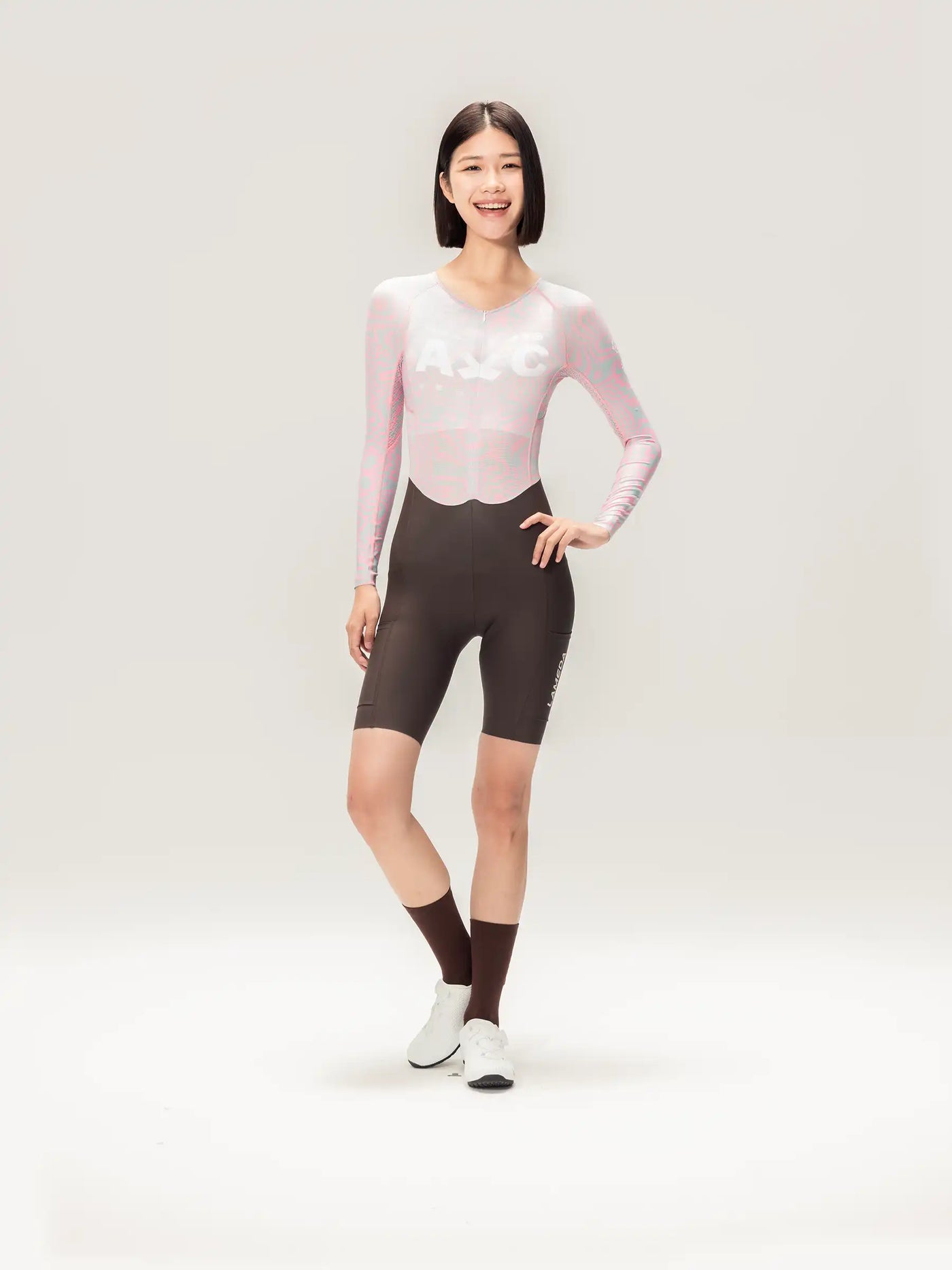 LAMEDA AC damernas långärmad skinsuit cykelbodysuit i rosa och svart med genomskinligt iriserande överdel och vit logotyp