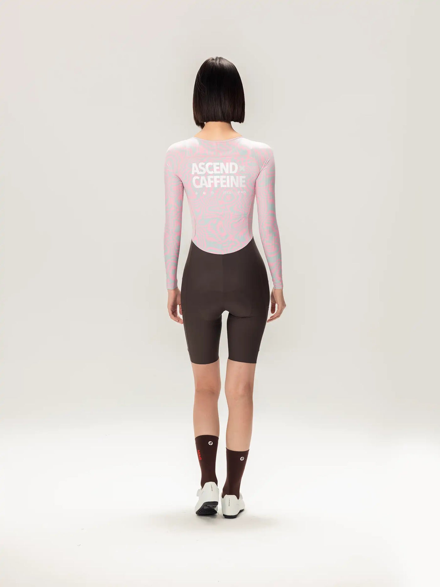 Bakvy av rosa långärmad LAMEDA a c dam skinsuit med ascend caffeine-tryck kombinerad med mörkbruna cykelshorts