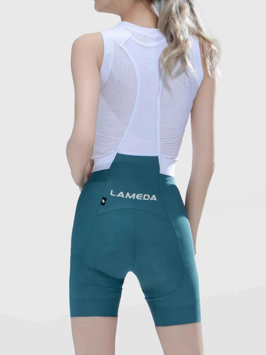 Achterkant van blauwgroene LAMEDA luminance vrouwen fietsbibbroek met witte merkmarkering op de achterzak in nevelblauw