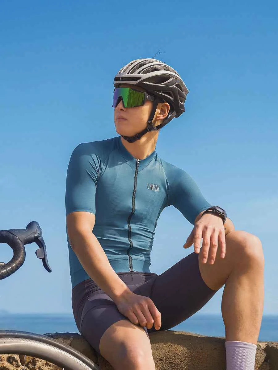 Czarno-szary aerodynamiczny kask rowerowy z zielonym lustrzanym wizjerem w parze z koszulką rowerową LAMEDA mody green