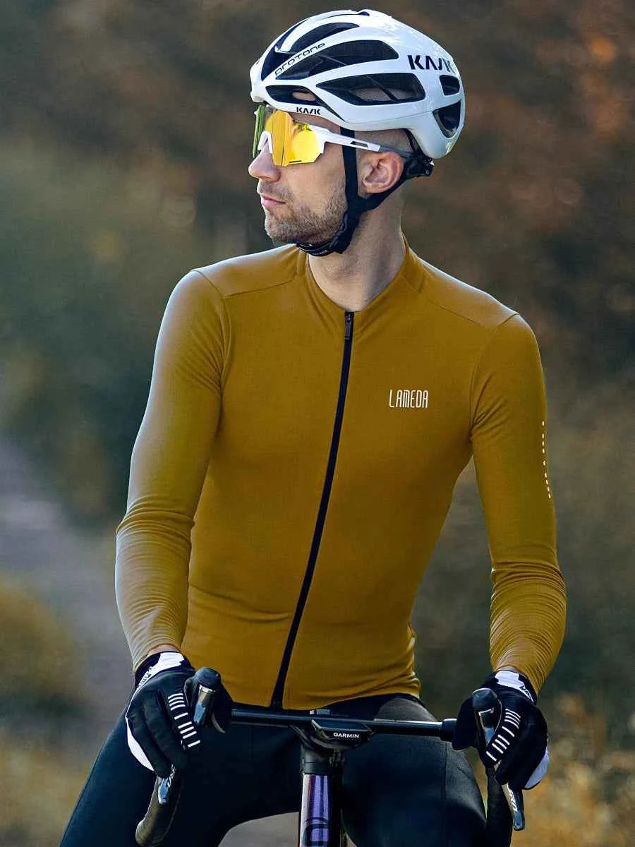 En man som bär vit kask hjälm och gultonade solglasögon modellerar LAMEDA trascend herr fleecefodrad termisk cykeltröja ockragul