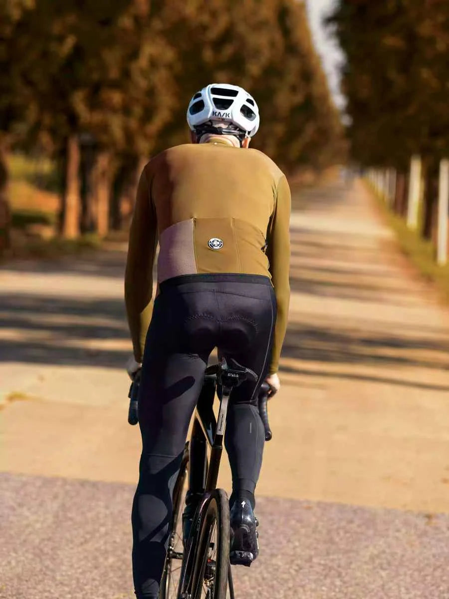 Vit kask cykelhjälm med svarta ventilationsspalter och diskret logotyp sedd från baksidan med LAMEDA trascend herrers cykeltröja ockragul