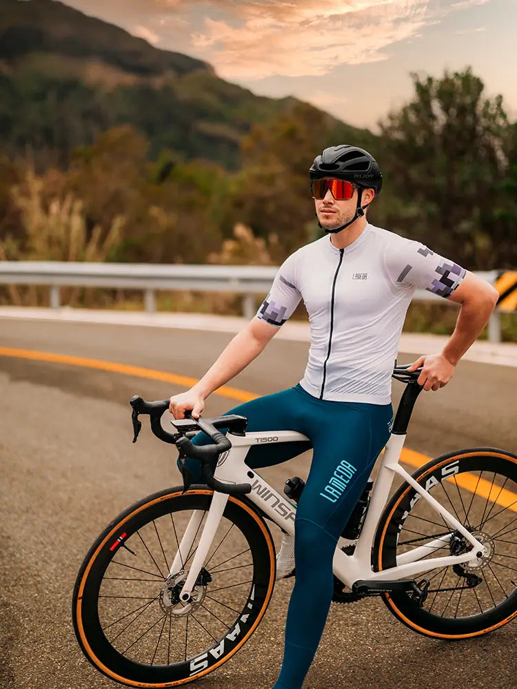 En vit vägcykel med svarta cykelstyr och däck med orange accenter kombinerad med en trendig herrcykeltröja med avslappnad passform