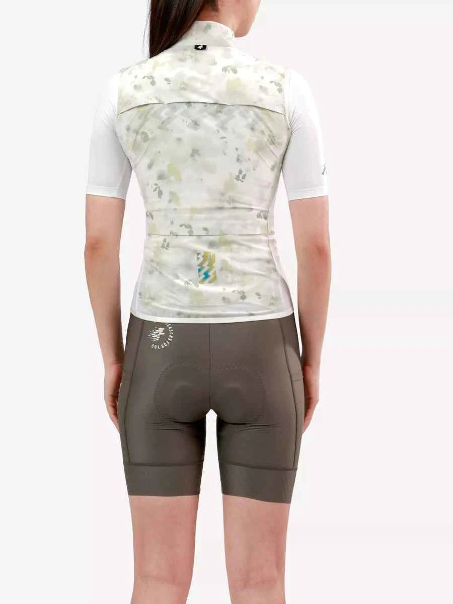 En kvinna bär LAMEDA lätt damcykväst i vit med abstrakt kamouflagemönster och mörkolivgröna shorts